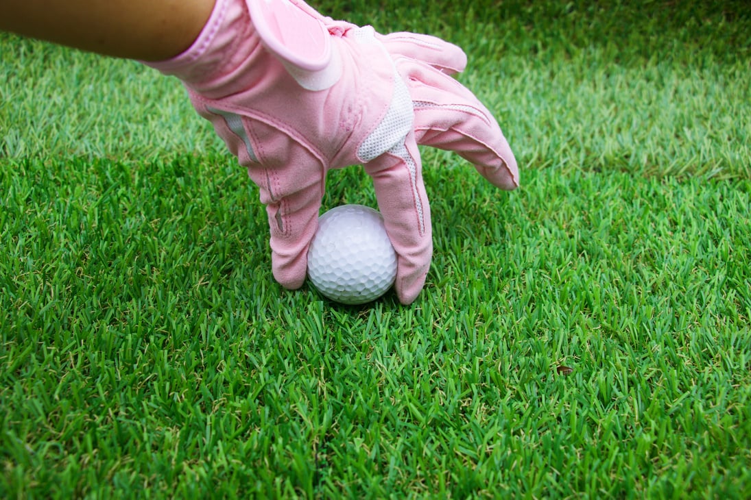 Lady golfer is holding golf ball on green gras